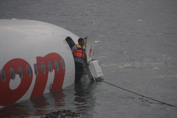 A rescue worker stands at the door of a Lion Air plane that missed the runway in Denpasar, Bali, in this picture provided by the Indonesian police, April 13, 2013. All safe as plane misses Bali runway, lands in sea