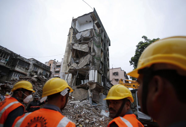 Rescue workers stand amid rubble at the site of a collapsed residential building in Mumbai early June 11, 2013. Mumbai building collapse kills 5